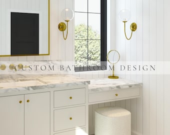 May include: A bathroom vanity with white cabinets, gold knobs, and a marble countertop. The space features a mirror with a gold frame, two gold wall sconces with glass globes, a gold vanity mirror, and a textured stool. Text reads CUSTOM BATHROOM DESIGN.