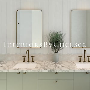 May include: A double vanity bathroom setup featuring two rectangular mirrors with thin bronze frames, white marble countertops, and sage green cabinets. Two bronze faucets are mounted above white sinks, with a vase of greenery in between.