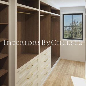 Puede incluir: Un vestidor con armarios blancos con herrajes dorados, estantes interiores de madera oscura y barras para colgar. La unidad incluye varios cajones y secciones de almacenamiento abiertas. Una ventana con marco negro es visible al fondo. Texto: InteriorsByChelsea.