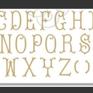 May include: A gold-colored alphabet with decorative flourishes. The letters are uppercase and include A through Z, as well as parentheses and two decorative symbols.
