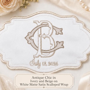 K&ouml;nnte beinhalten: Ein wei&szlig;es, mattes Satin-Tuch mit gewelltem Rand und einer gestickten Monogramm-Applikation der Buchstaben C und B in beigem Garn. Unter dem Monogramm ist der Text July 18, 2026 in Beige gestickt. Die R&auml;nder sind mit einer beigen Borte versehen.