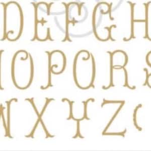 May include: A complete set of uppercase alphabet letters from A to Z in a light tan, decorative serif font with ornate flourishes. The characters are arranged in three rows, followed by a pair of parentheses and two small decorative bracket symbols.