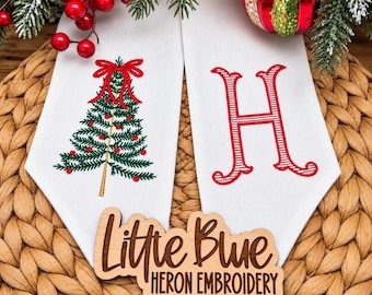 May include: Two white fabric panels featuring machine embroidery. The left panel displays a green Christmas tree with red ornaments and a red bow. The right panel features a large red letter H with white horizontal stripes.