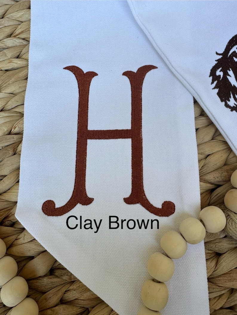 May include: White canvas banner with a large brown embroidered letter H and the text "Clay Brown" below it.