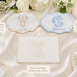 K&ouml;nnte beinhalten: Drei matte Satin-Wickelt&uuml;cher mit gestickten Monogrammen und Daten. Ein Tuch ist beige und elfenbeinfarben mit dem Text Antique Chic in Beige and Ivory, eines ist hellblau mit Vintage Vine in True Light Blue und eines ist elfenbeinfarben mit Antique Chic in Ivory.