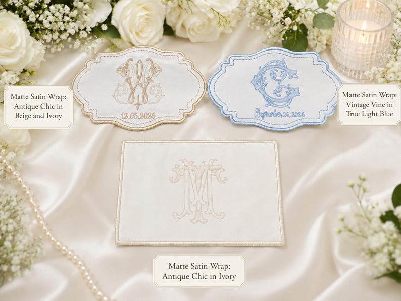 K&ouml;nnte beinhalten: Drei matte Satin-Wickelt&uuml;cher mit gestickten Monogrammen und Daten. Ein Tuch ist beige und elfenbeinfarben mit dem Text Antique Chic in Beige and Ivory, eines ist hellblau mit Vintage Vine in True Light Blue und eines ist elfenbeinfarben mit Antique Chic in Ivory.