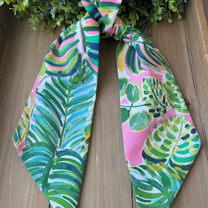 May include: A green and pink patterned fabric hair scarf with a tropical leaf design.