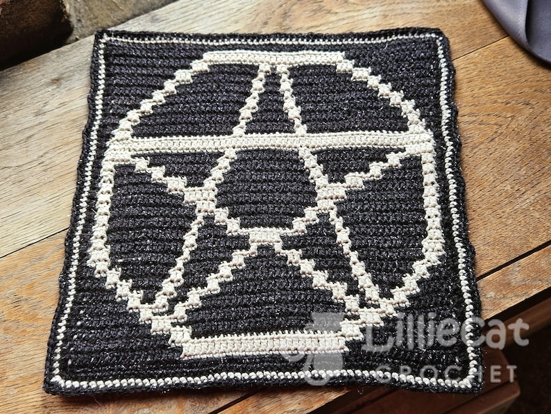A crochet pattern using overlay mosaic crochet technique. The pattern has a dark background with a white pentagram motif in the middle. The watermark says Lilliecat crochet. It has an alternative and witchy feel.