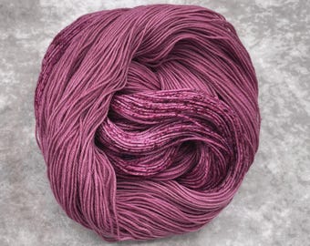May include: A skein of deep pink yarn with a subtle shimmer. The yarn is wound into a ball shape and is ready for knitting or crocheting.