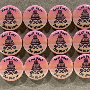 May include: Twelve pink and orange round buttons with the text "Knit Fast Die Warm" and a stylized image of a knitted hat and crossed knitting needles.