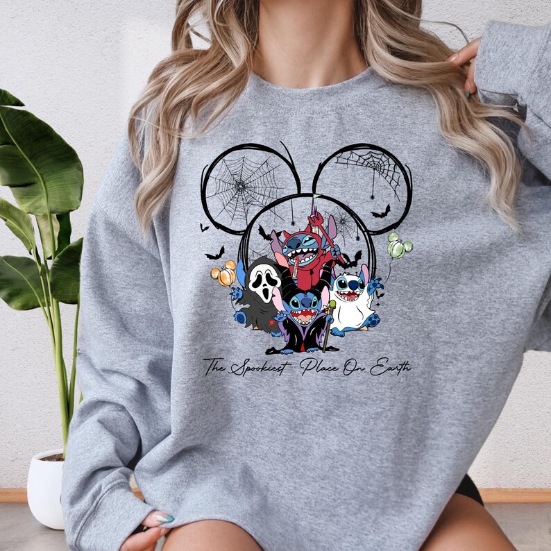 A gray sweatshirt with a graphic design featuring characters from the Disney movie Lilo & Stitch, including Lilo, Stitch, and other Disney characters, along with a spider web and bats.