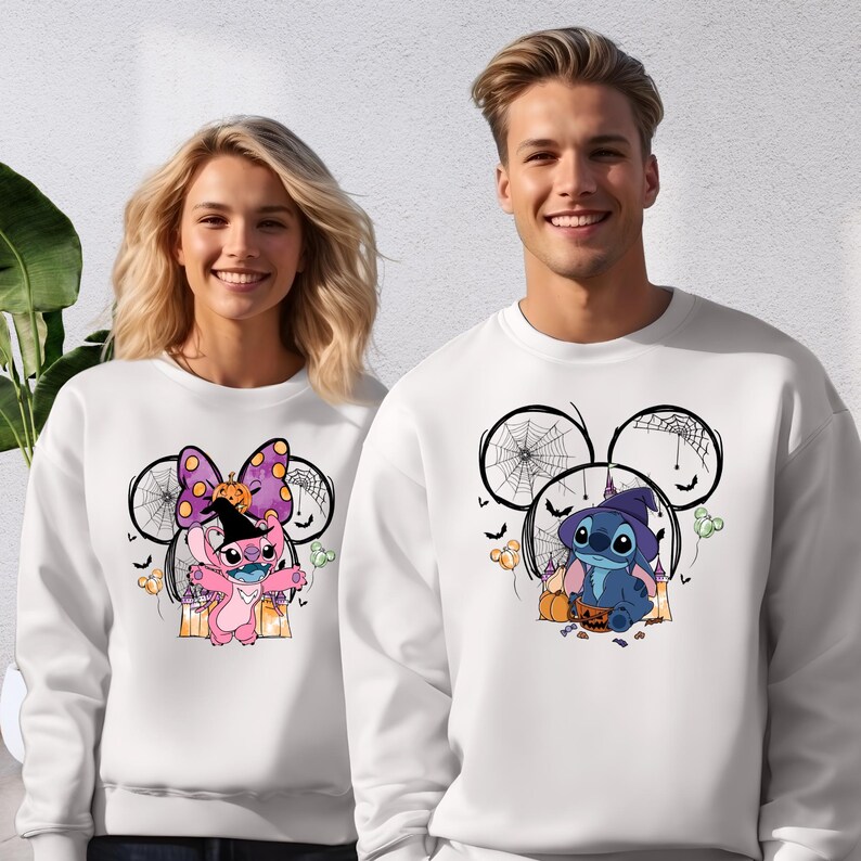 A man and a woman are standing together, both wearing white sweatshirts with cartoon characters and Halloween-themed designs.