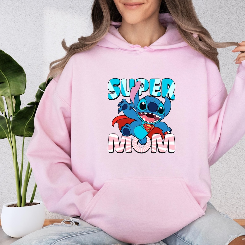 a woman wearing a pink hoodie that says super mom