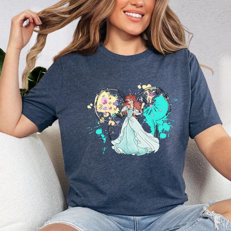 a woman sitting on a white couch wearing a disney princess t - shirt