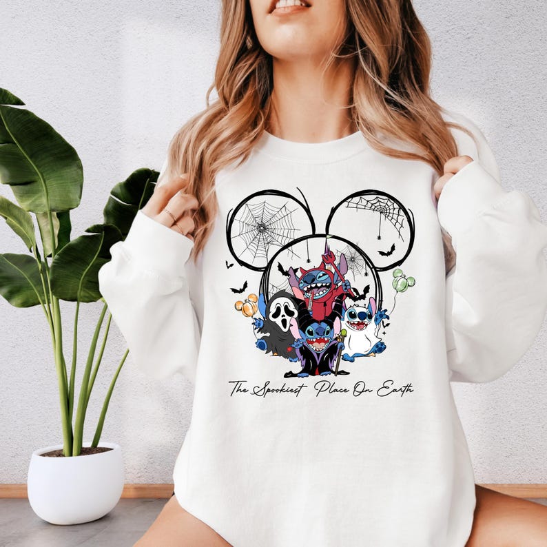 A woman wearing a white sweatshirt with a graphic design featuring a character from Disney's "The Darkest Place on Earth".