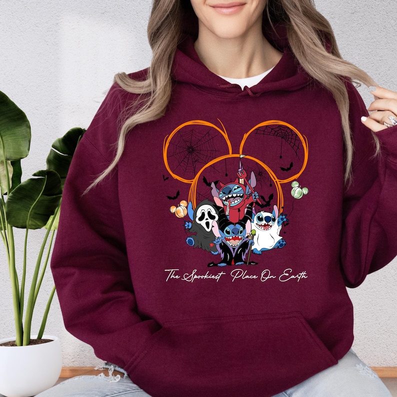 A woman wearing a burgundy hoodie with a graphic design featuring characters from the Disney movie "Stitch".