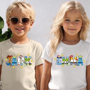 May include: Two children wearing t-shirts with personalized names. The shirt on the left says "JACK" with colourful cartoon character designs. The shirt on the right says "EMMA" with similar designs. Both shirts have yellow star accents.