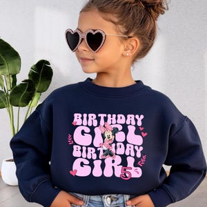 a little girl wearing a birthday girl sweatshirt
