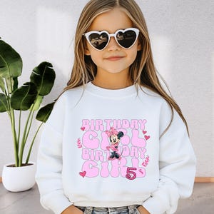 a little girl wearing sunglasses and a sweatshirt