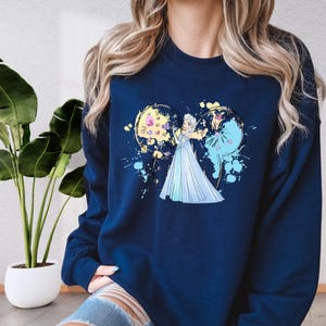 a woman wearing a blue sweatshirt with a picture of a bride and groom on it