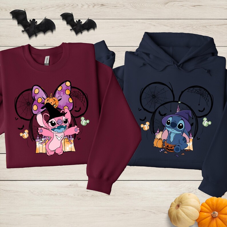 two sweatshirts with Halloween-themed designs, including characters from the Disney movie Lilo & Stitch. The sweatshirts are displayed on a wooden surface, with bats and pumpkins scattered around them.