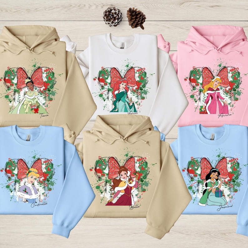 A collection of six Disney princess-themed hoodies, each with a different character and color, arranged on a wooden surface.