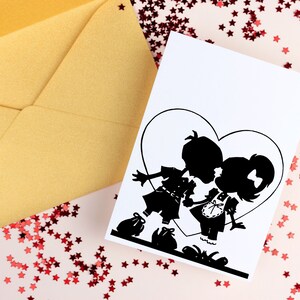May include: A white card with a black silhouette of a couple kissing inside a heart shape. The card is surrounded by red glitter stars on a pink background.