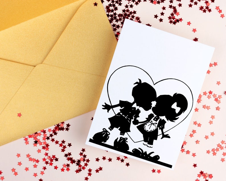 May include: A white card with a black silhouette of a couple kissing inside a heart shape. The card is surrounded by red glitter stars on a pink background.