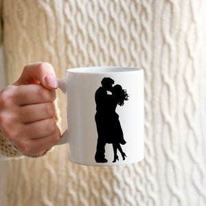 May include: White ceramic mug with a black silhouette of a couple kissing. The mug has a handle on the right side.