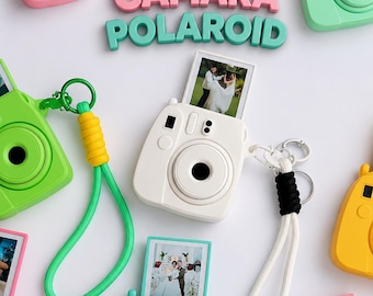 May include: A collection of miniature camera keychains in various pastel and bright colors, including white, pink, yellow, green, and purple. Each keychain features a small photo insert, a wrist strap, and a metal ring for attachment.