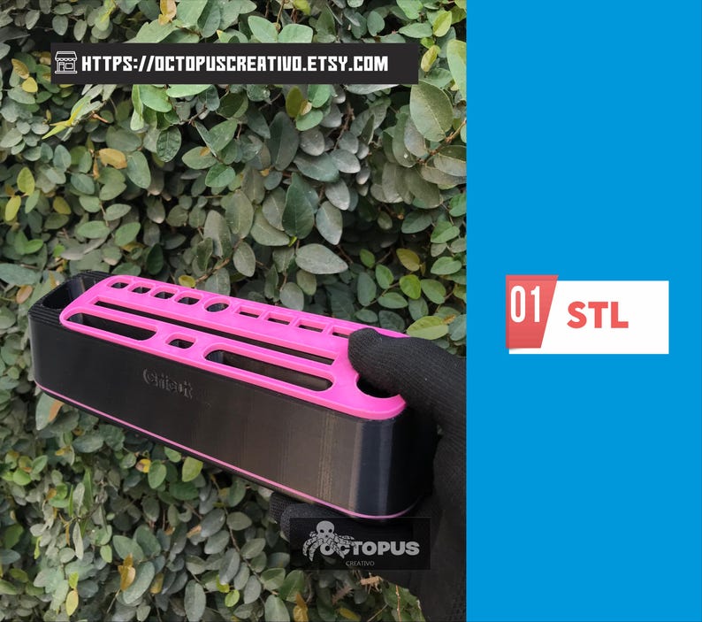 May include: A black and pink organizer with multiple slots, held by a gloved hand against a backdrop of green foliage. The organizer has the text "Octopus Creativo" and the text "01 STL".