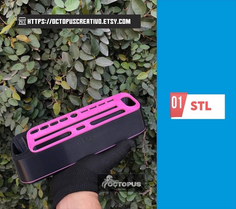 May include: A black and pink rectangular object with a series of holes and slots, held by a gloved hand. The object has the text "01 STL" on a white and red rectangle. The background is a green leafy plant.