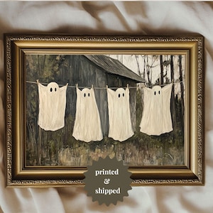 May include: A painting of four white ghosts hanging on a clothesline in front of a rustic wooden building. The ghosts have two eyes and are painted in a realistic style.