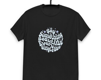 Könnte beinhalten: Schwarzes T-Shirt mit einem weißen Kreisdesign, auf dem "Say Something Beautiful Every Single Day" mit blauen Blumenakzenten steht.