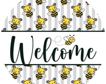 May include: A round sign with a white background and a gray striped pattern. The sign features cartoon bees and the word "Welcome" in black script. A cute bee is flying near the word "Welcome".