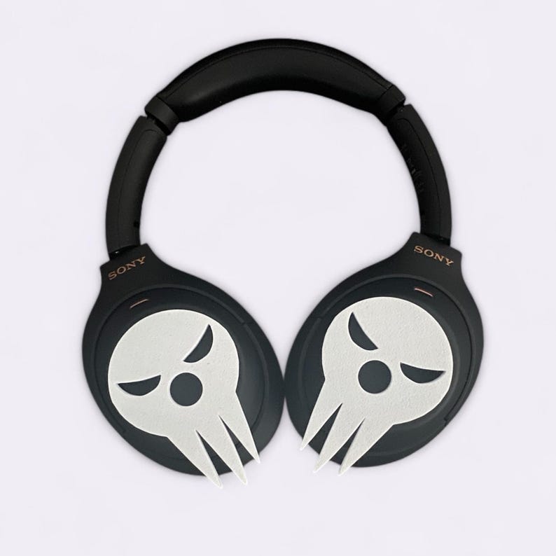Op de afbeelding: Zwarte over-ear hoofdtelefoon met een wit schedelontwerp op elke oorschelp. De hoofdtelefoon heeft het woord "SONY" op elke oorschelp gedrukt.