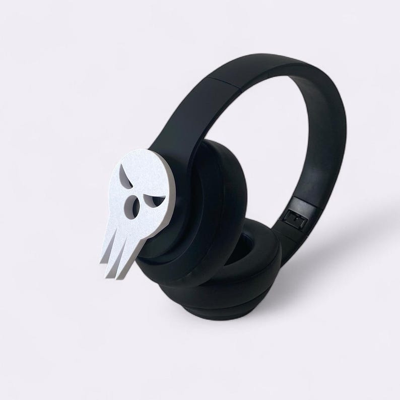 Peut inclure: Casque audio noir avec un embl&egrave;me de cr&acirc;ne blanc sur le c&ocirc;t&eacute;. Le casque est dot&eacute; d'un design de coussinet d'oreille rembourr&eacute; et d'une esth&eacute;tique &eacute;l&eacute;gante et moderne. L'embl&egrave;me de cr&acirc;ne ajoute une touche unique et audacieuse.