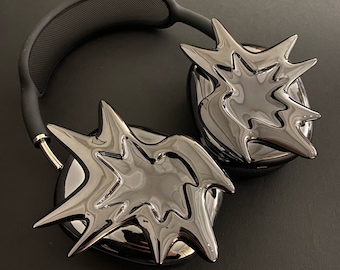May include: A pair of black headphones with a unique, abstract design. The earcups are shaped like a starburst and have a glossy finish.