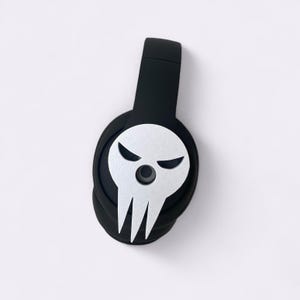 Peut inclure: Casque audio noir avec un motif de cr&acirc;ne argent&eacute; sur l'&eacute;couteur. Le cr&acirc;ne a une orbite oculaire circulaire et trois dents pointues. Le casque a un bandeau rembourr&eacute;.