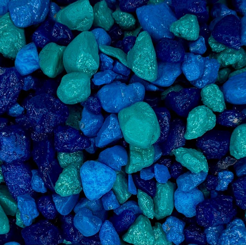 May include: A close-up image of a collection of small, smooth, blue and teal colored stones. The stones are arranged in a random pattern, creating a visually appealing texture.