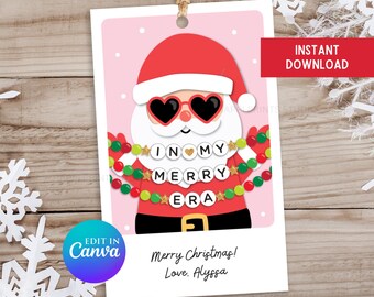 May include: A pink Christmas gift tag featuring a cartoon Santa Claus wearing sunglasses and a beaded necklace spelling "In My Merry Era". The tag includes the text "Merry Christmas! Love. Alyssa" and "Happi Prints Studio".