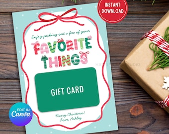 May include: A Christmas-themed gift card with a light blue background and a red border. The card reads "Enjoy picking out a few of your FAVORITE THINGS" and "GIFT CARD". A wrapped gift and pine branches are in the background. The text "Merry Christmas! Love, Ashley" is also present.