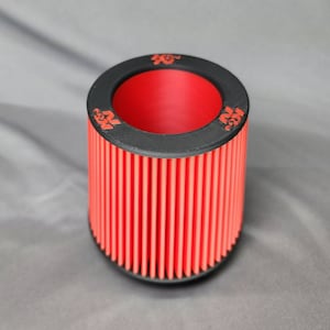 May include: Red cylindrical air filter with black top and K&N branding. The filter has a ribbed design.