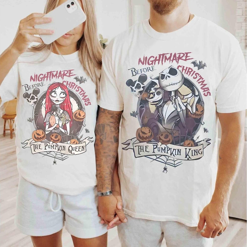 Puede incluir: Camisetas blanquecinas con un dise&ntilde;o gr&aacute;fico de "Pesadilla antes de Navidad". Una camiseta dice "The Pumpkin Queen" con Sally, calabazas y murci&eacute;lagos. La otra dice "The Pumpkin King" con Jack Skellington, calabazas y murci&eacute;lagos.