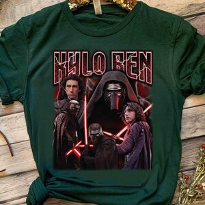 May include: Dark green t-shirt with a graphic of Kylo Ren from Star Wars. The design includes images of Kylo Ren with red lightsabers and the text "KYLO REN" in a bold, stylized font. The shirt is made of a soft material.