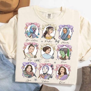 May include: Cream-coloured t-shirt featuring illustrations of Star Wars female characters, each framed with a decorative border and a bow. Characters include Bo-Katan, Padmé, Ahsoka, Rey, Leia, Hera, Jyn, Sabine, and Qi'ra. The shirt is made of a soft material.