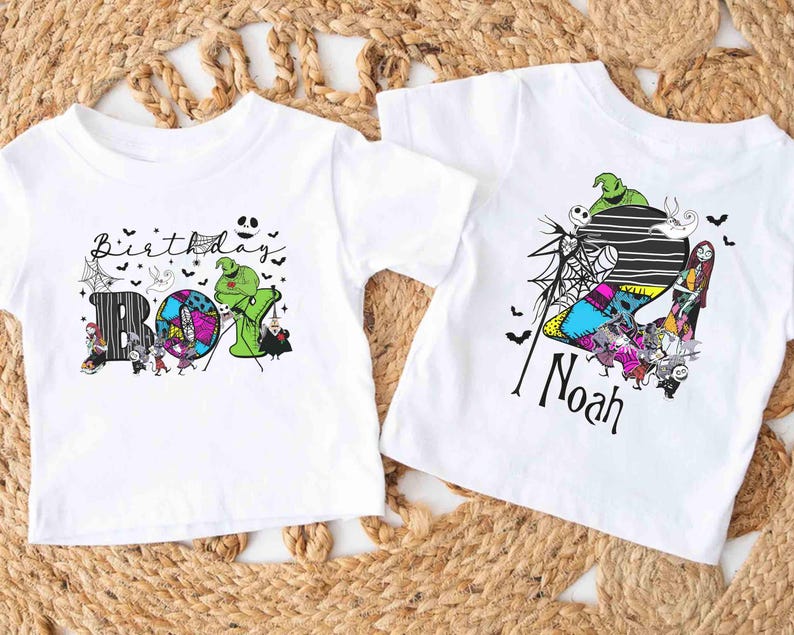May include: Two white t-shirts with Halloween-themed graphics. One shirt says "Birthday Boy" with a colorful design featuring characters. The other shirt has the name "Noah" and a similar design with characters and a striped background.