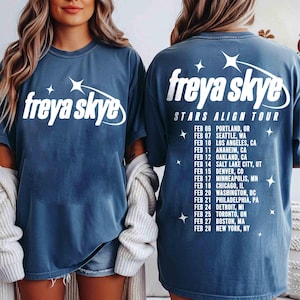Könnte beinhalten: Blaue T-Shirts mit dem Text "freya skye" und "Stars Align Tour" in Weiß aufgedruckt. Die Tourdaten und -orte sind auf der Rückseite des Shirts angegeben. Die Shirts haben eine bequeme Passform.