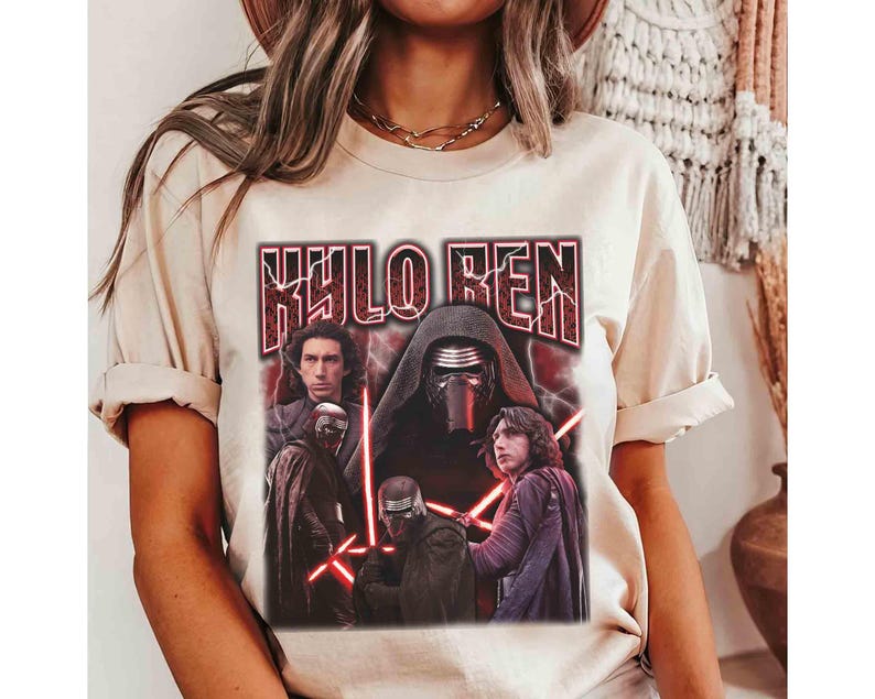 May include: A cream-coloured t-shirt with a graphic of Kylo Ren from Star Wars. The design includes the text "KYLO REN" in a distressed, red font, and images of Kylo Ren and other characters with red lightsabers.