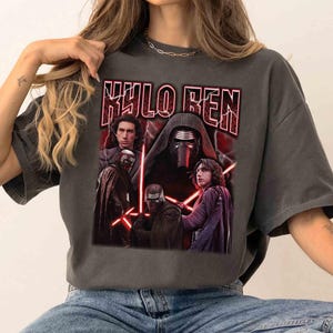 May include: Dark grey t-shirt with a graphic of Kylo Ren from Star Wars. The design includes images of Kylo Ren and the text "KYLO REN" in a red, distressed font. The shirt has a vintage, worn appearance.